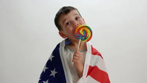 Young boy wrapped in american flag licks giant lollipop - spoiled Stock Footage 142297270