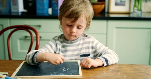 Young Boy Writing With Chalk On Small Blackboard Stock Footage 100042954