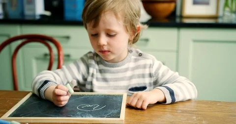 Young Boy Writing With Chalk On Small Blackboard Stock Footage 100042964