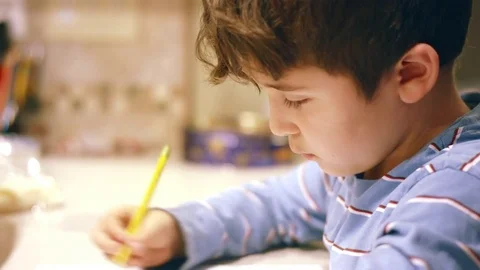 Young boy writing drawing and doing homework at dinner table Video stock 71048259