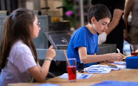 Young boy writing in notebook while girl listens carefully at a desk indoors 写真素材