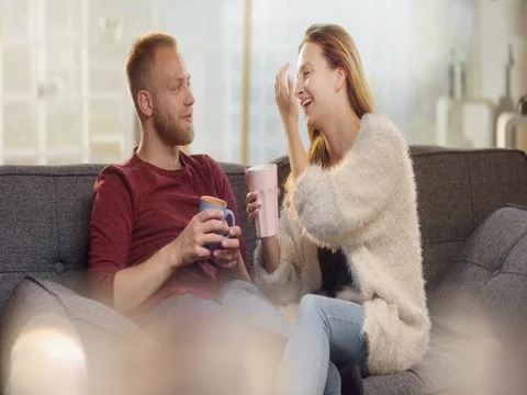 Young boyfriend removing a wisp from his girlfriend while drinking tea on a c Video stock 78024340