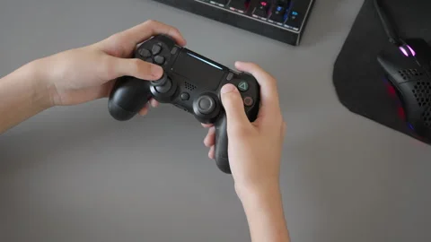 A young boy's hands on a controller playing a video game, top-down view Stock Footage 315289627