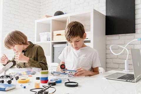 Young boys having fun constructing robot cars at the workshop Stock Photos