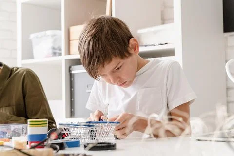 Young boys having fun constructing robot cars at the workshop Stock Photos
