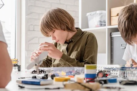Young boys having fun constructing robot cars at the workshop Stock Photos