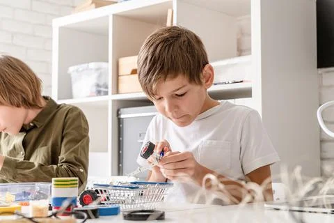 Young boys having fun constructing robot cars at the workshop Stock Photos