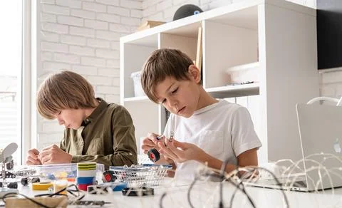 Young boys having fun constructing robot cars at the workshop Stock Photos