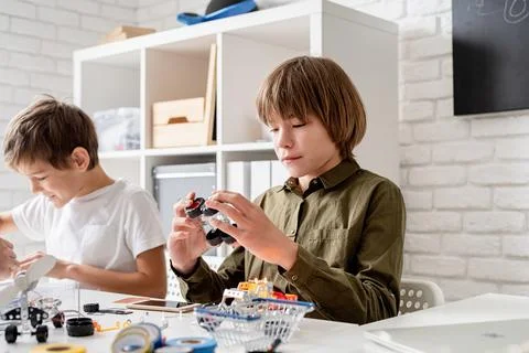 Young boys having fun constructing robot cars at the workshop Stock Photos