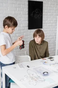 Young boys having fun constructing robot cars at the workshop Stock Photos