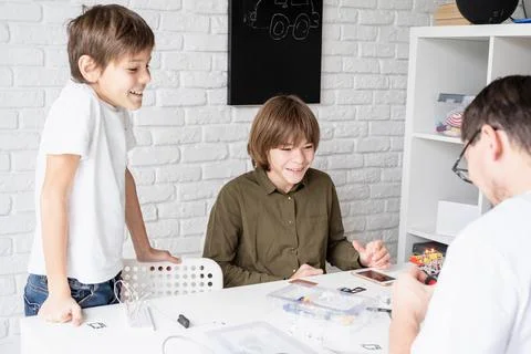 Young boys having fun constructing robot cars at the workshop Stock Photos