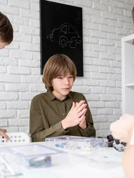 Young boys having fun constructing robot cars at the workshop Stock Photos
