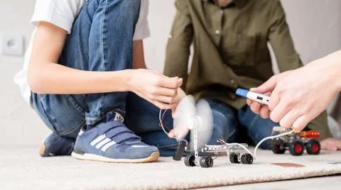 Young boys having fun constructing robot cars at the workshop Stock Photos