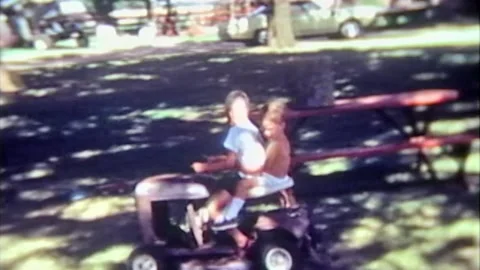 Young boys having fun riding a powered lawnmower Stock Footage 194521563