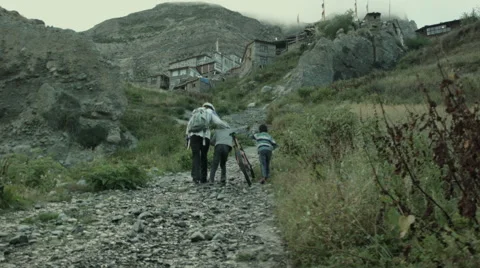 Young boys help cyclists climb a hill Stock Footage 64314366