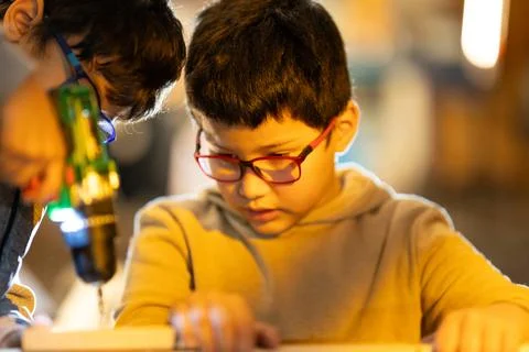 Young boys learning practical skills using a drill Foto stock