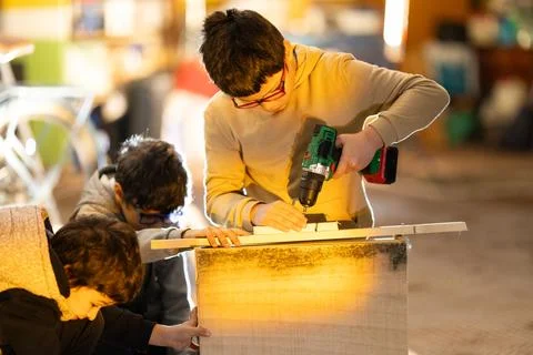 Young boys learning woodworking using a power drill Foto stock