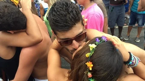 Young Brazilian couples kiss in the middle of the crowd during a carnival street Stock Footage