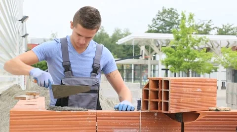Young brick layer working outside on brick wall construction Stock Footage 51558629