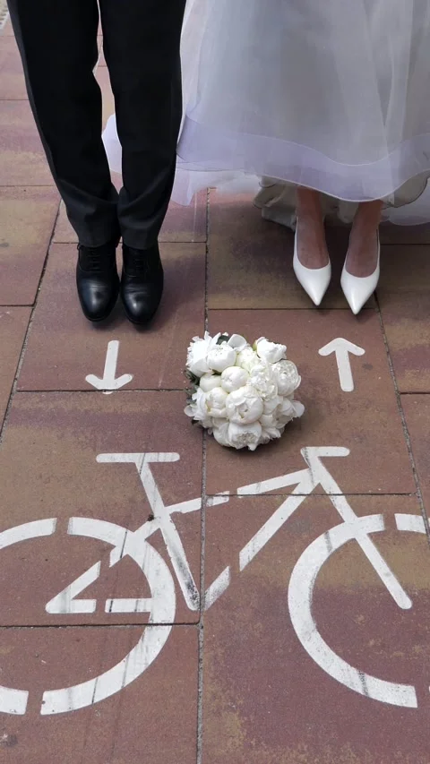 A young bride and groom jump onto a bicycle path toward the markings. Close-up. Stock Footage 337369859