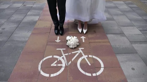 A young bride and groom jump onto a bicycle path toward the markings. Close-up. Stock Footage 337369911