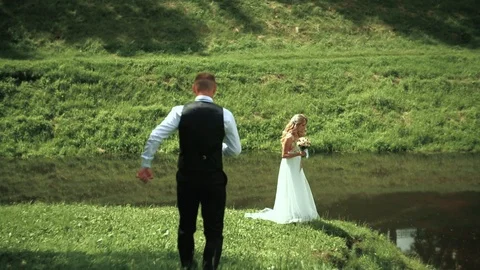 Young bride and groom posing near the river in the autumn. Wedding day. Stock Footage 95473364