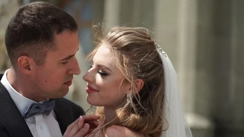 Young bride and groom posing in a city. Waving veil at windy summer day. Stock Footage 102410492