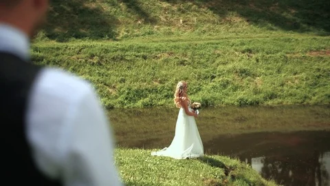 Young bride with a bouquet in her hands posing near the river. Wedding day. Stock Footage 95473353