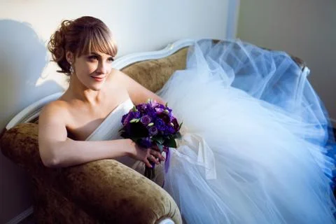 Young bride with flowers on the sofa Stock Photos