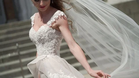 Young bride posing in a city. Waving veil at windy summer day. Stock Footage 102410437