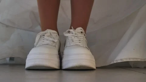 The young bride put on sneakers and lowered her dress, covering her shoes Stock Footage 260971726