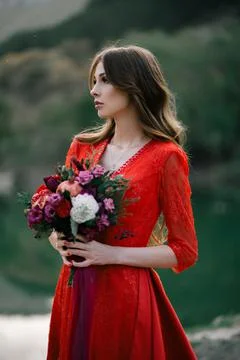 Young bride in a red dress with an Assemtric bouquet of pomegranates and roses. Stock Photos