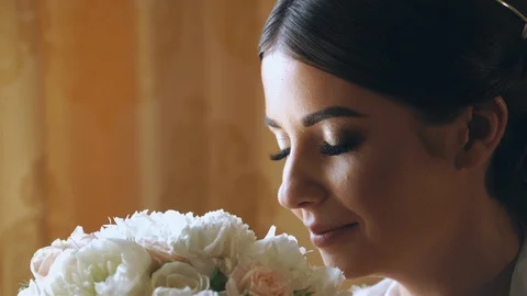 Young bride is sitting by the window in a luxury hotel with a bouquet of flowers Vidéo 105683299