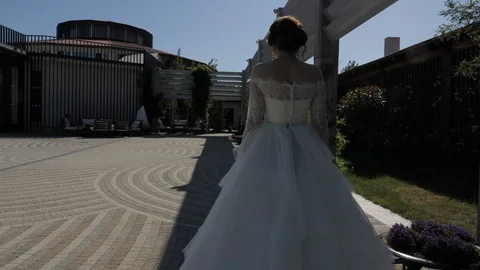 Young bride wearing stylish long dress walks along yard Stock Footage 122582289