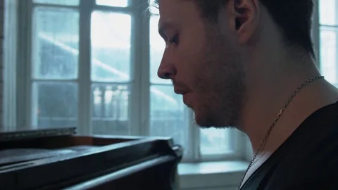A young British man is singing against the window. A handsome man with a silver Stock Footage 75069971