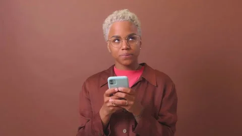 Young brooding flirting African American woman holding smartphone in hands Stock Footage 225401848