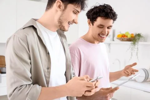 Young brothers using tablet computer and mobile phone in kitchen Stock Photos
