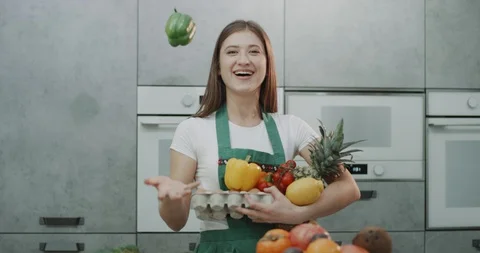 A young brown haired girl throwing and catching a pepper while giggling. 4k Stock Footage 100151202