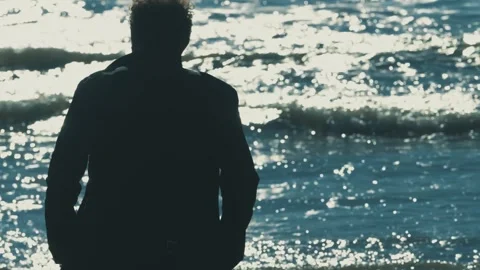 Young brown haired man from behind shaken looking at sea Stock Footage 332418891