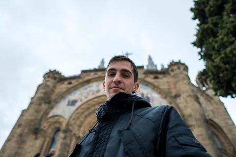 Young brown haired man in front of the church looking at camera. Winter Stock Photos