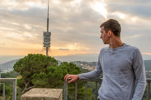 Young brown haired man looking at the electric tower behind him from the moun Stock Photos
