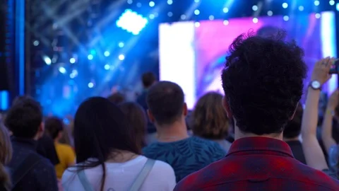 Young brown-haired man shakes his head in rhythm looking at the stage at a Stock Footage 118138992