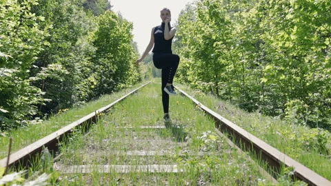 Young brunette in a black suit performs physical exercises on the background of Vídeos de archivo 89857852
