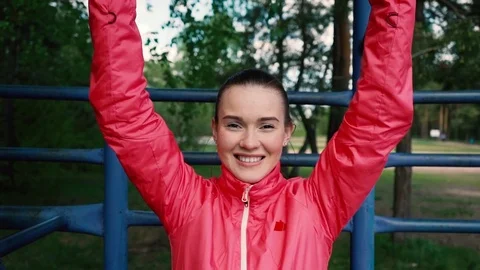 Young brunette doing chin-ups on the gym bar outdoors 스톡 동영상 75976751