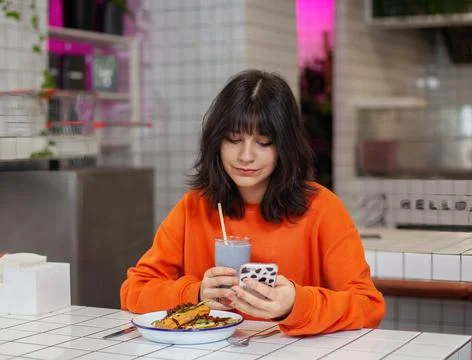 A young brunette girl in a cafe eats drinks a smoothie Stock Photos