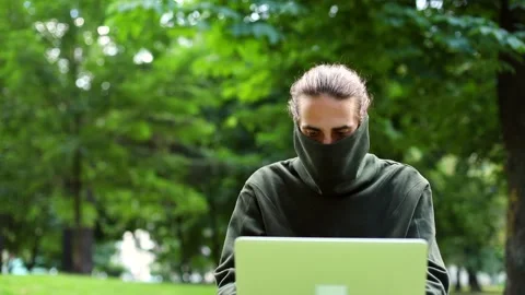Young brunette hacker man using laptop in park outside in pandemic city. Urban 스톡 동영상 146792877