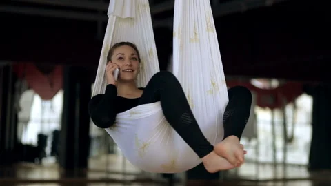 Young brunette is making call while lying in hammock indoors. Video stock 86469588