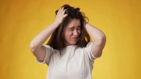Young brunette making distressing gestures against yellow background Stock Footage 247969688