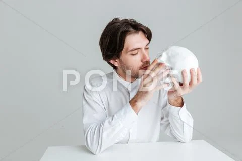 Young brunette man kissing fake skull Stock Photos