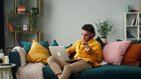Young brunette man using laptop for shopping, entering pin code from bank credit Stock Footage 156102523